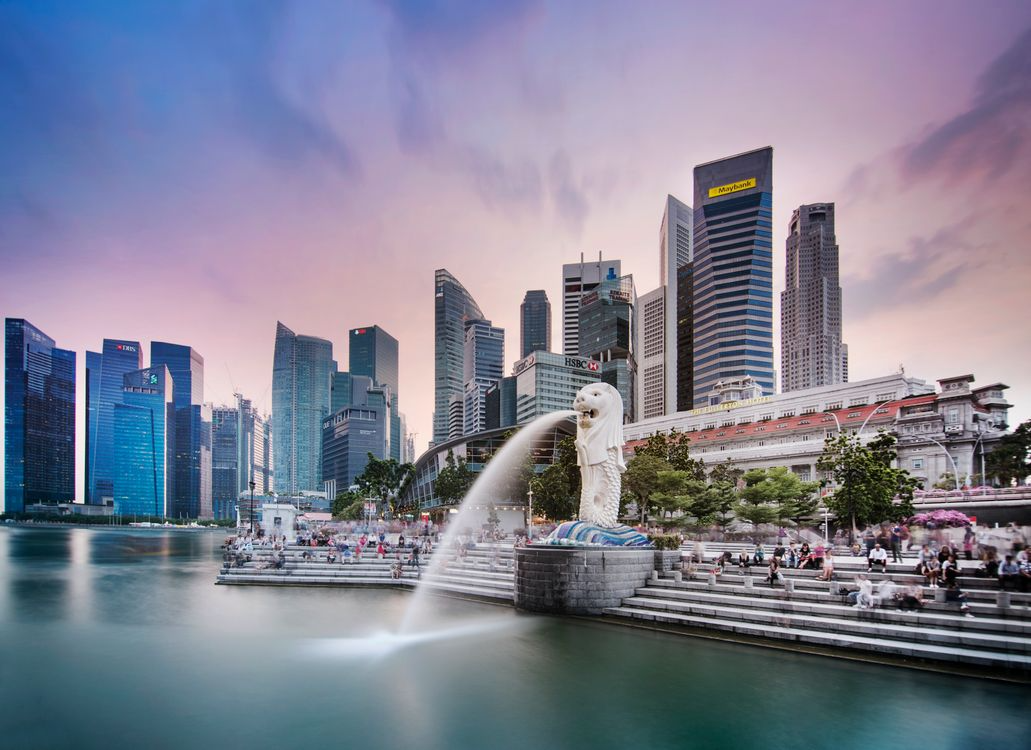 Merlion statue spouting water with Singapore skyline in the background.